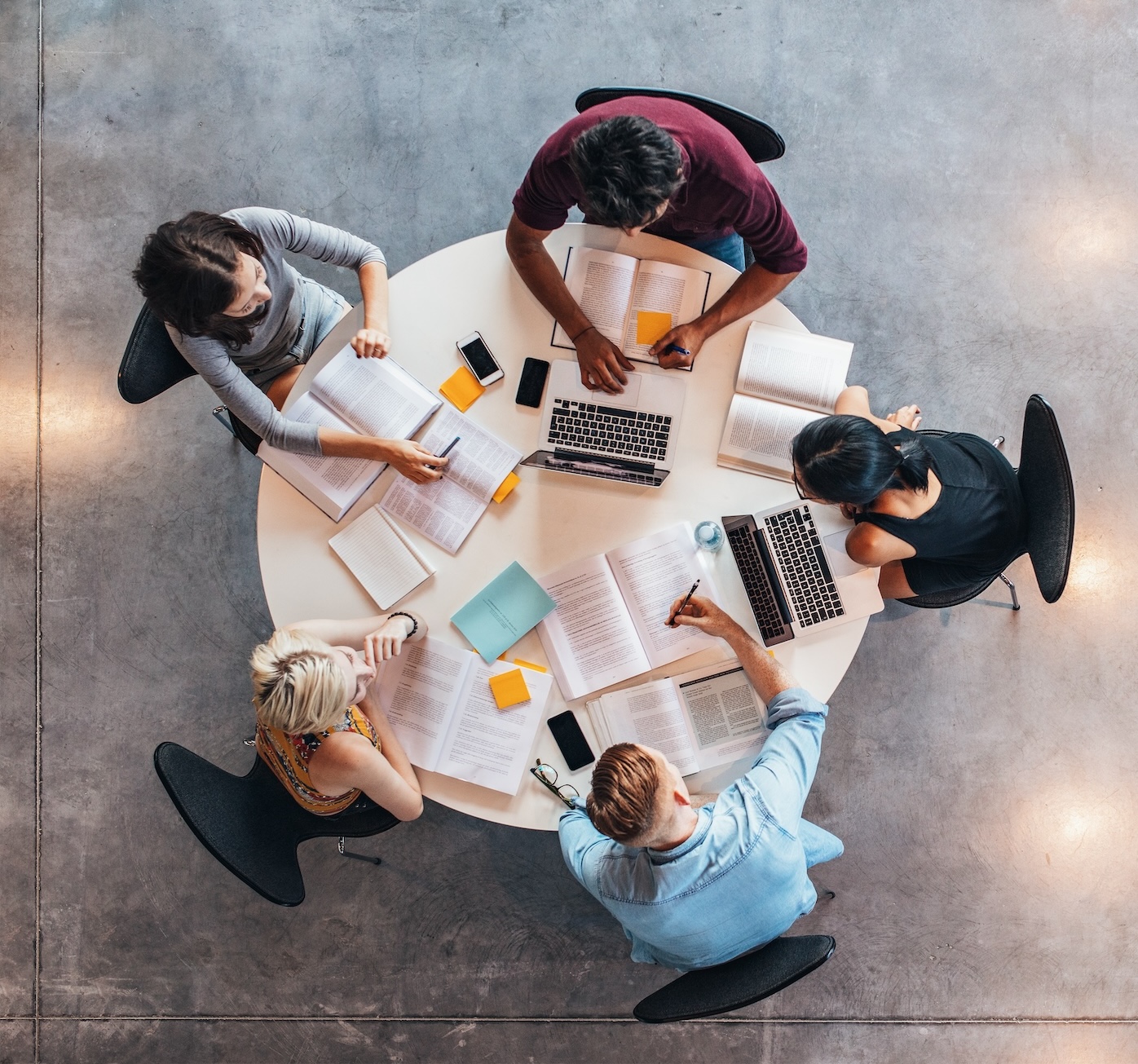 Aerial photograph of five people sitting out a round table working together.