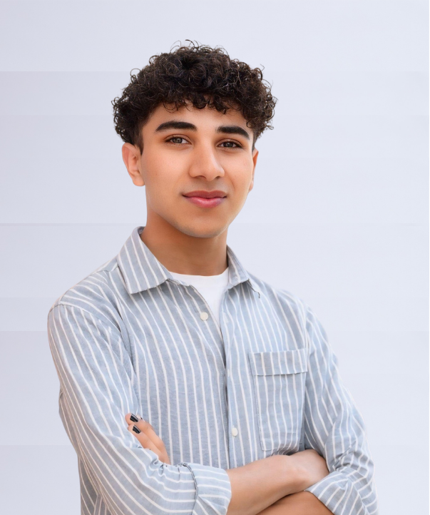 Profile shot of Hamza Zia, wearing a lined collared shirt with his arms crossed in front.